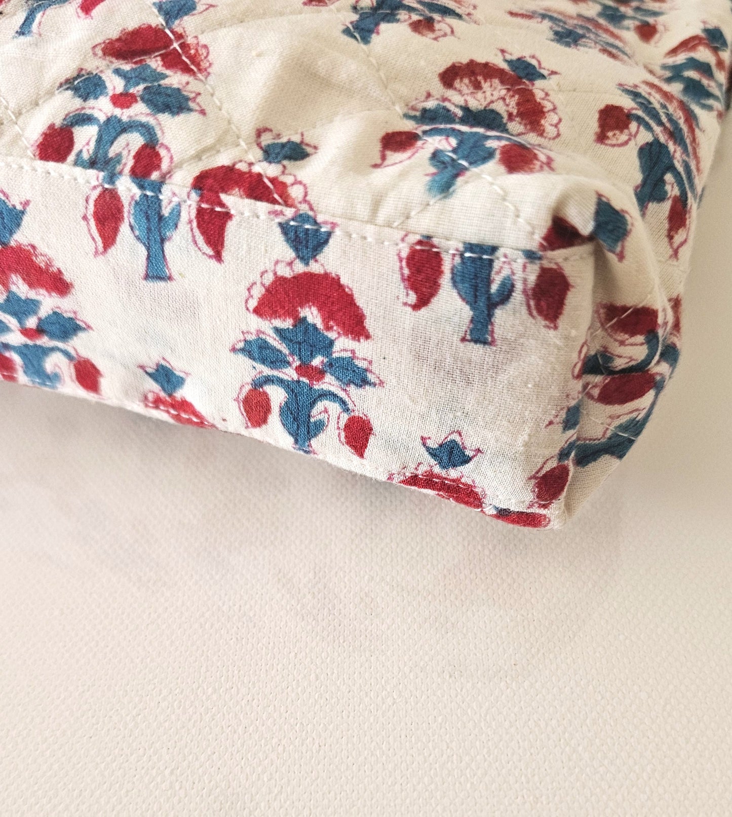 Quilted fabric with red and blue floral pattern on a white background