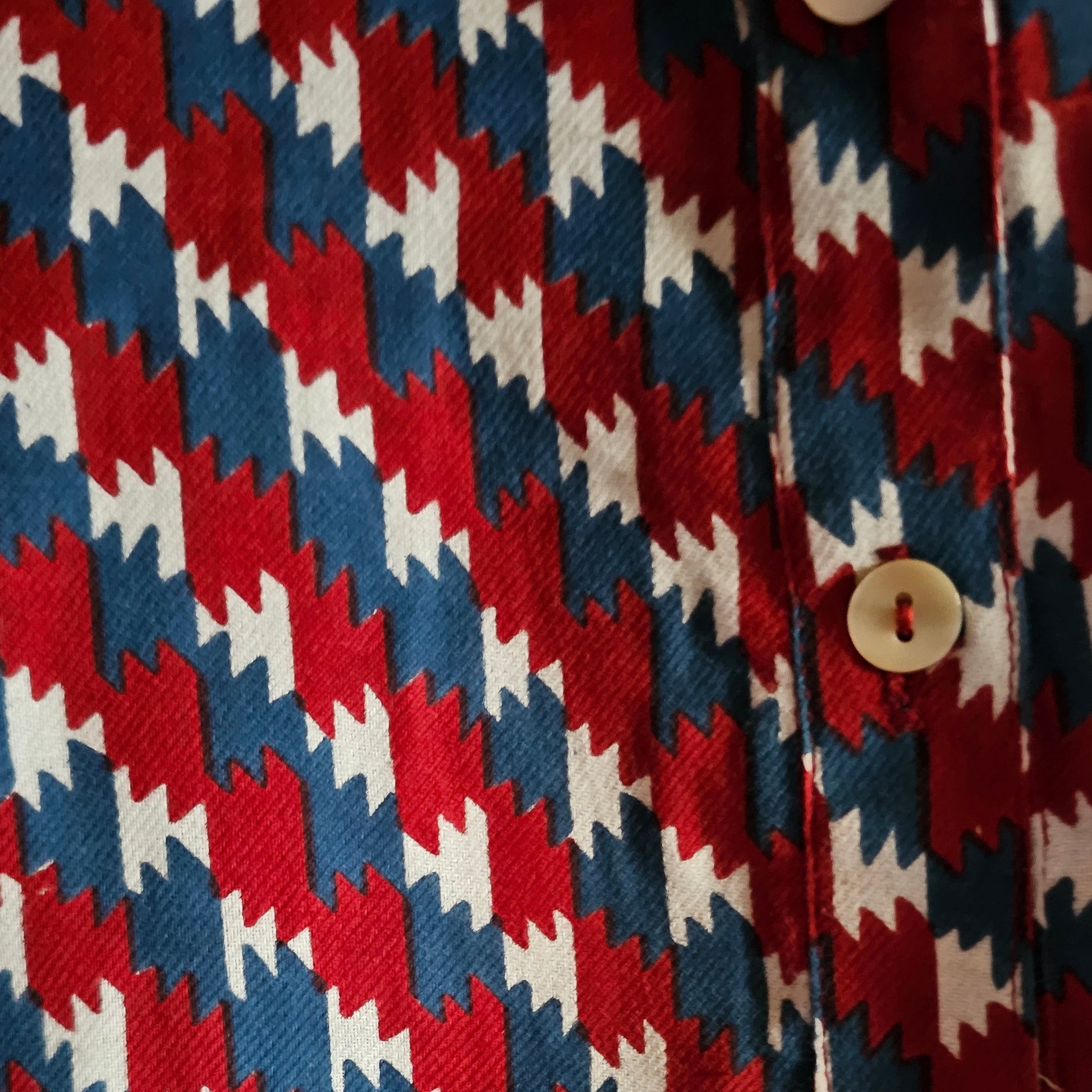 Close-up of a fabric with a red, white, and blue geometric pattern.