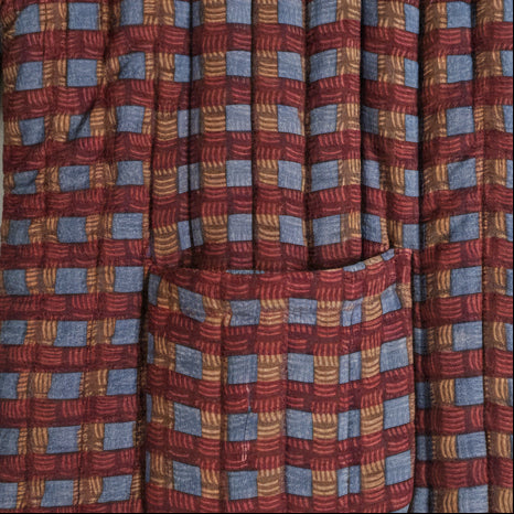 Close-up of a patterned fabric with red, blue, and brown colors.
